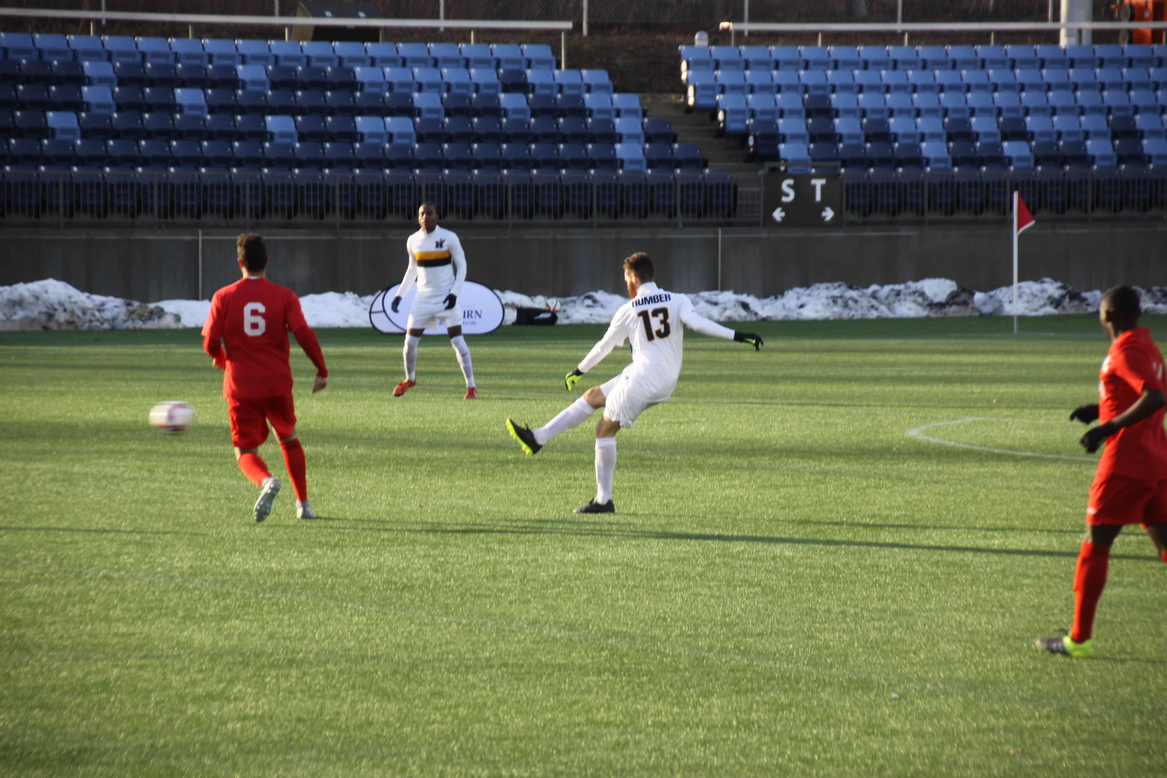 Humber player #13 kicks soccer ball on field