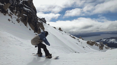 Snowboarder backflips on a snowy mountain
