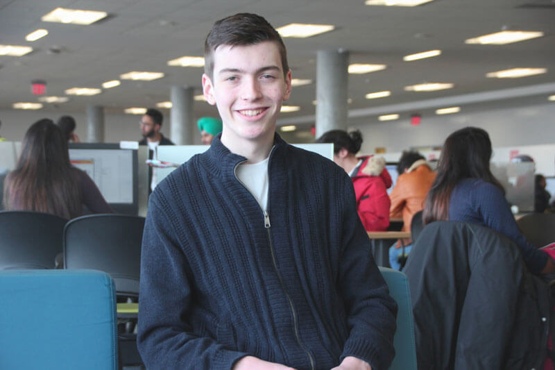 Drew Campbell smiling with computer lab in background
