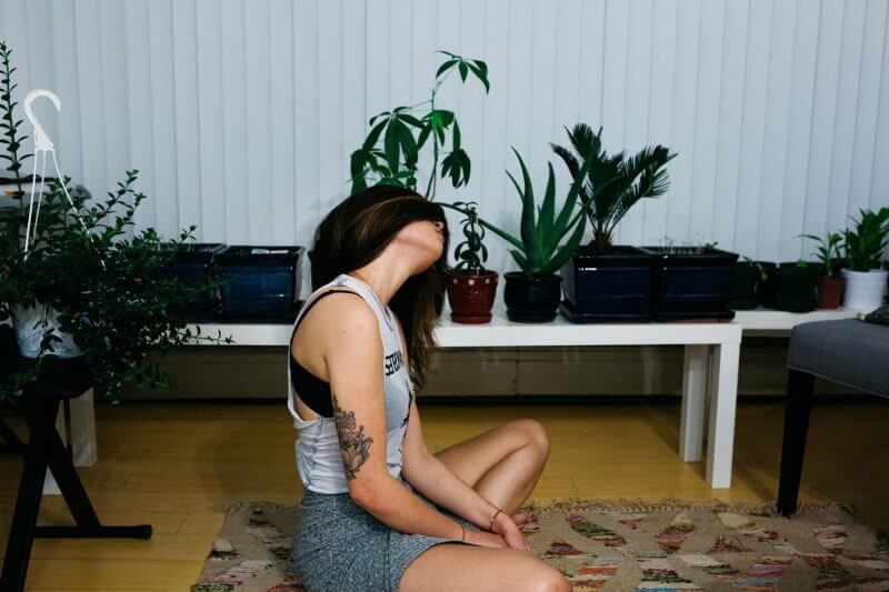 girl meditating with plants in living room