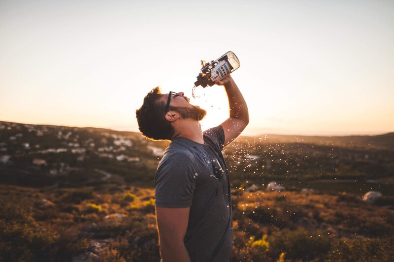 Man on a hike dumps water into mouth