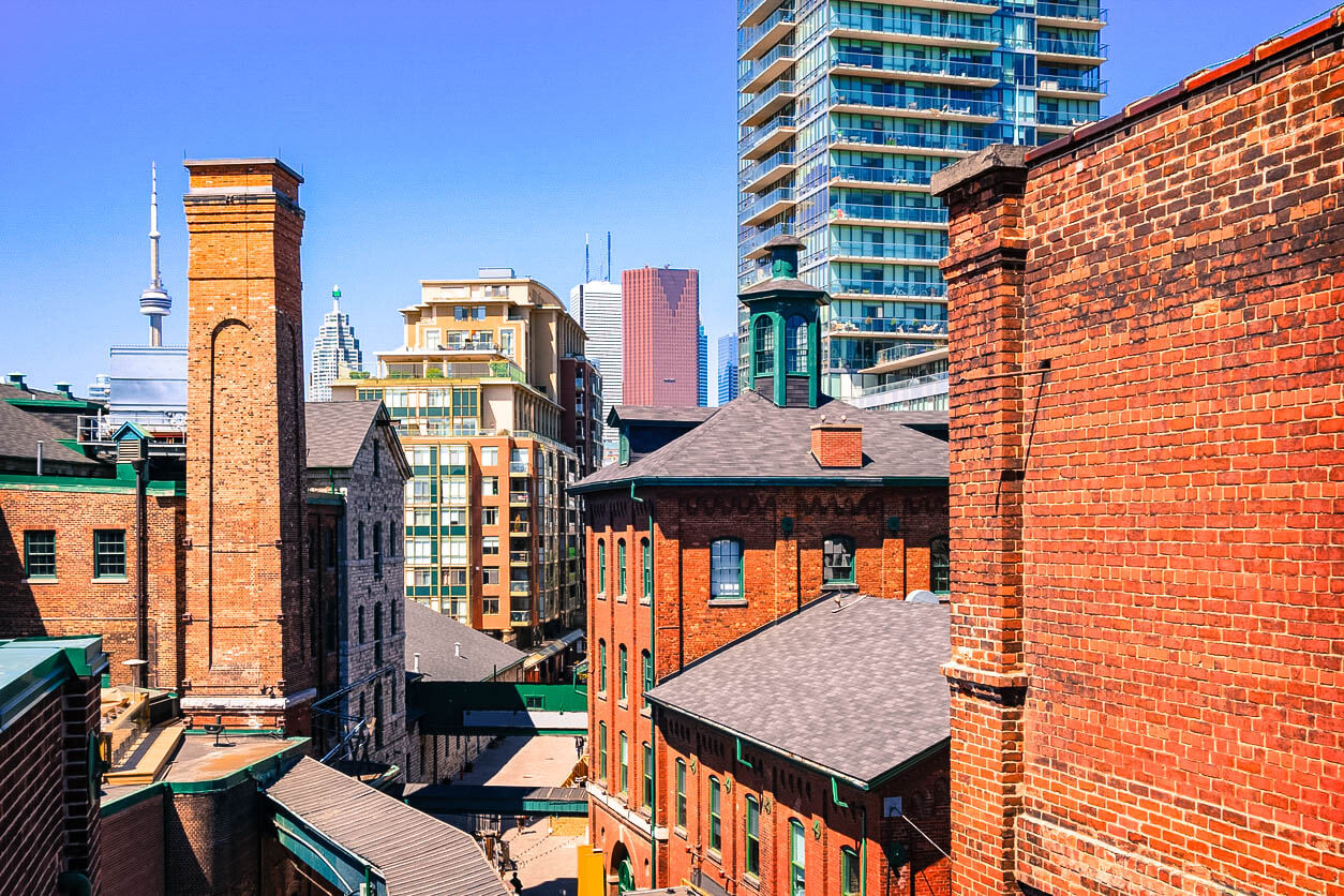 Photo of old brick towers of the chic Distillery District with new condos and downtown skyscrapers in the background