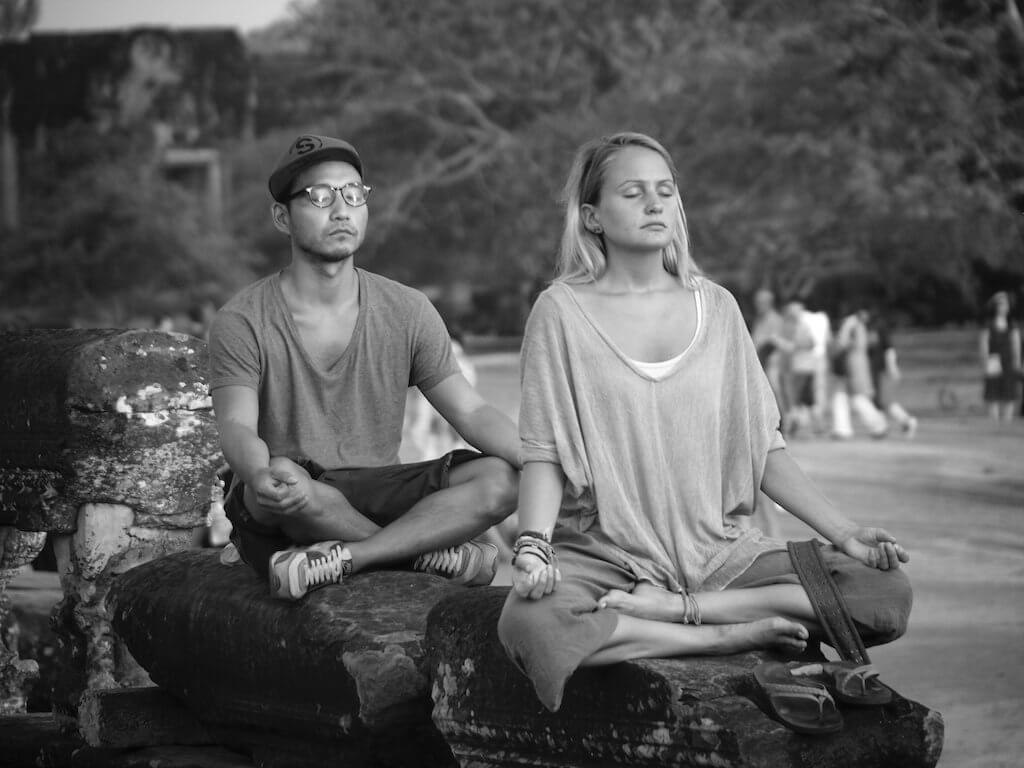 Man and woman meditating while sitting on rocks