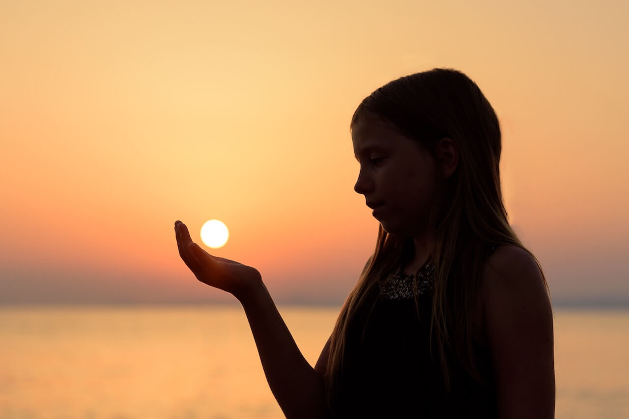 Silhouette of a girl cupping sunset