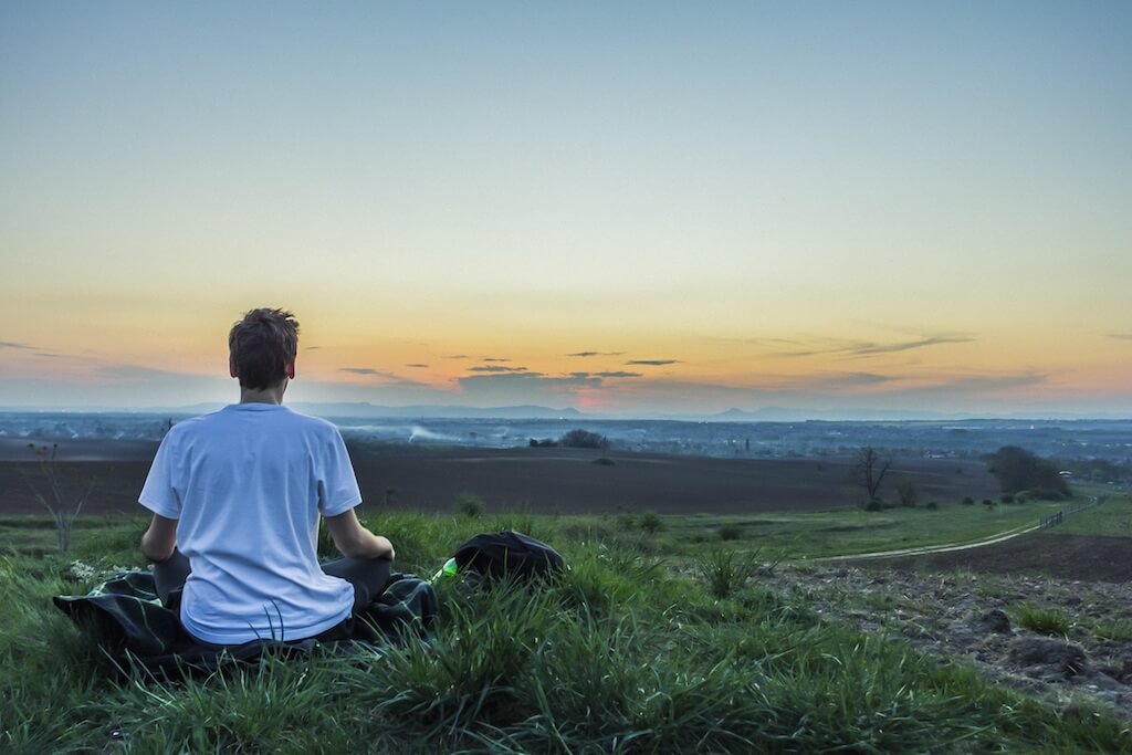 Man meditates in front of a sunset