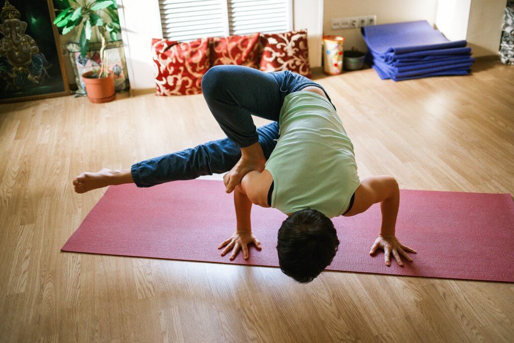 Person performing yoga position on a mat in a living room space
