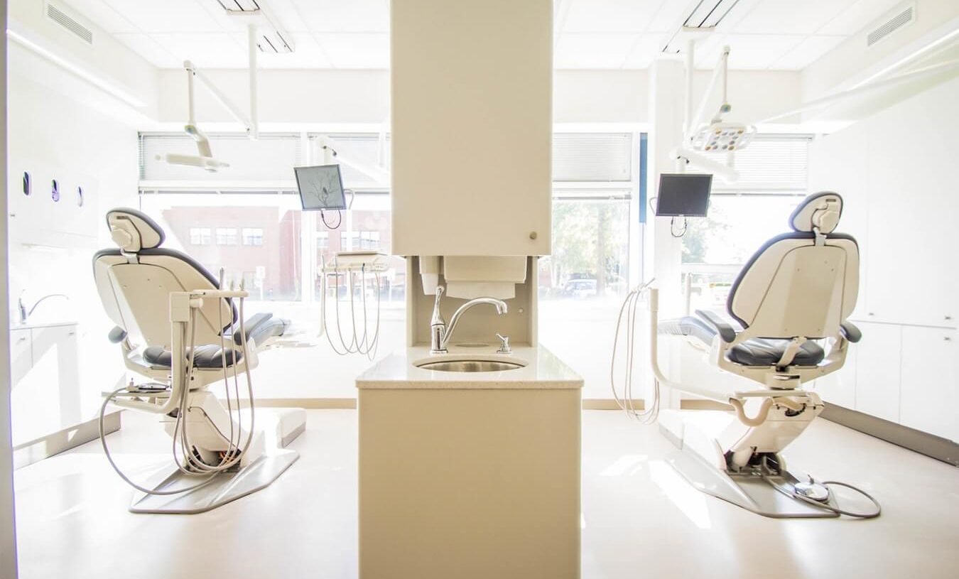 two dental chairs facing a window, separated by a sink