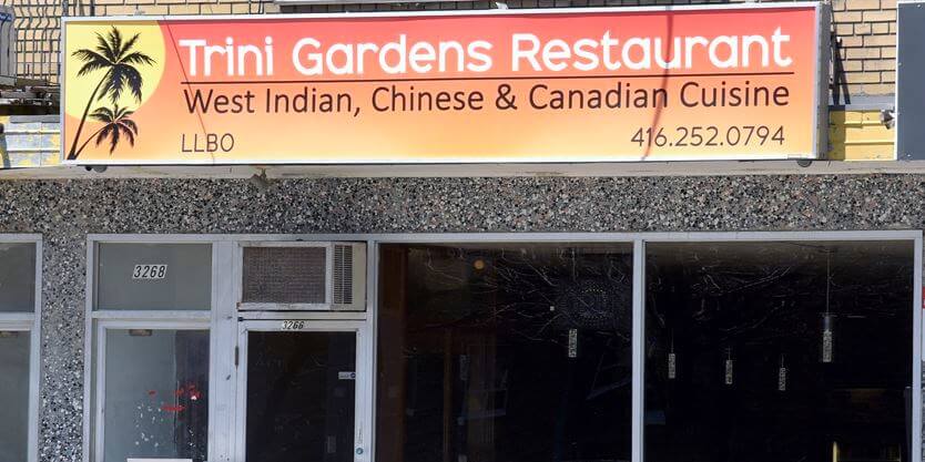 View of the sign and storefront of Trini Gardens restaurant on Lake Shore.