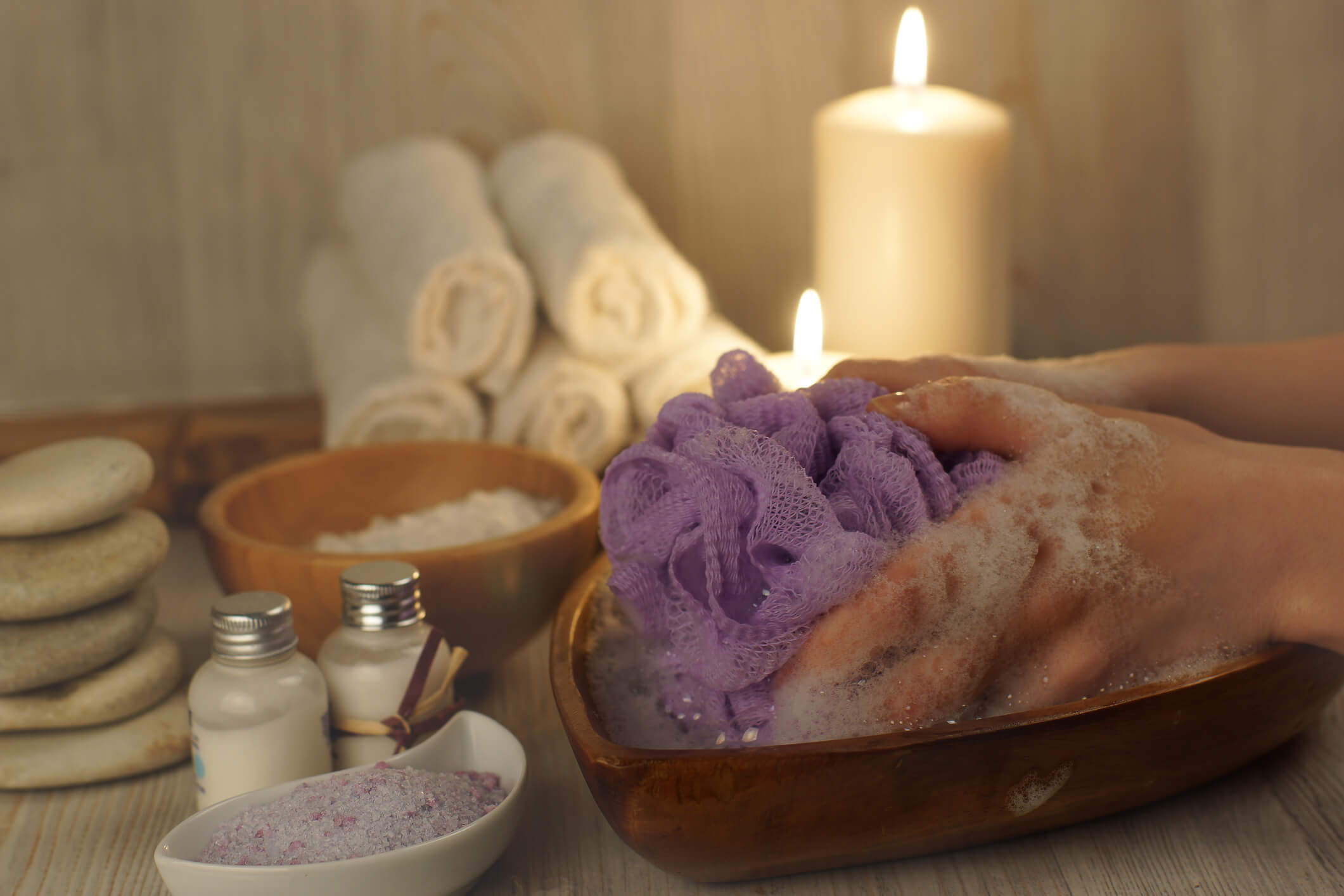 Hands with a washcloth in soapy water on a background of a set for spa procedures