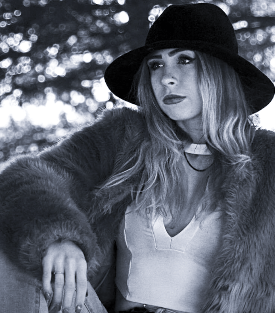 girl sitting with fur coat and hat on, looking into distance