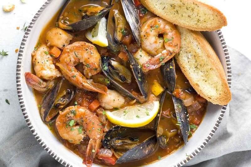 Seafood soup with shrimp and mussels. Bread on side.