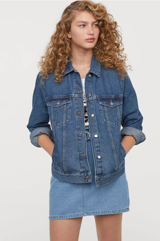 Curly haired woman wearing jean jacket and jean skirt