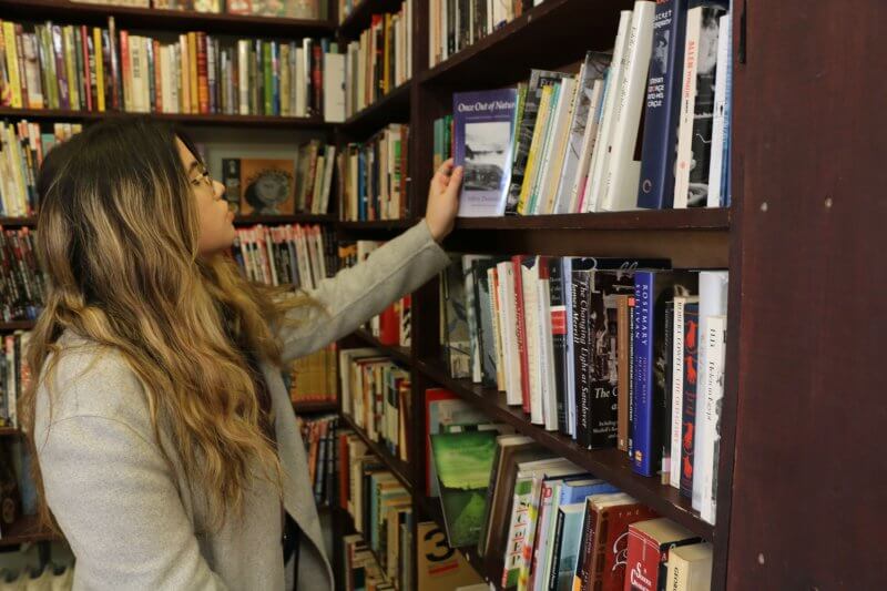 Girl in front of bookshelf picking out books