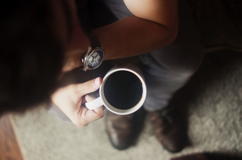 man holding coffee cup, wearing watch