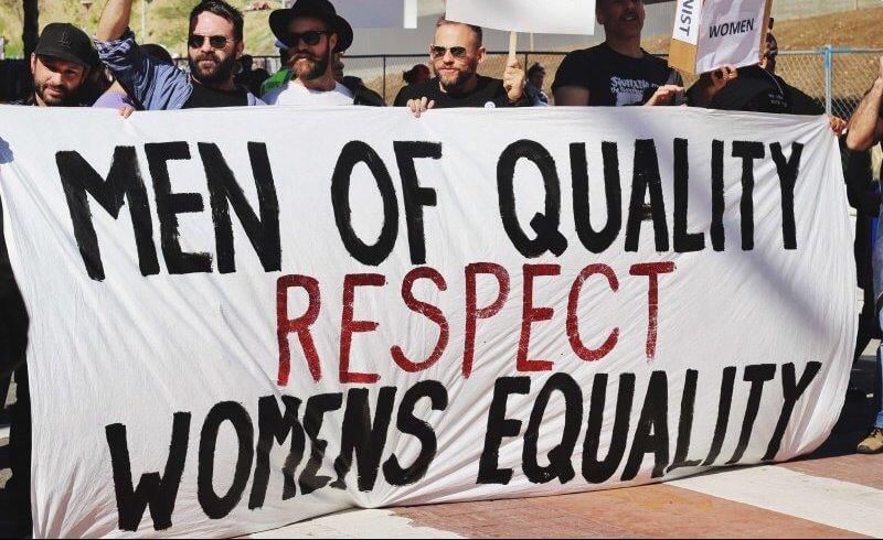 Men holding banner that reads "Men of quality respect women's equality"