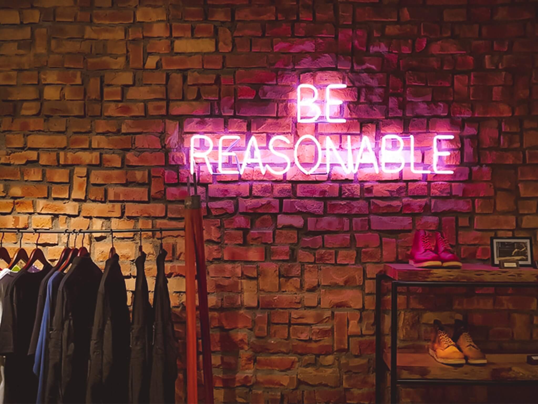 Be Reasonable neon sign with folded clothing