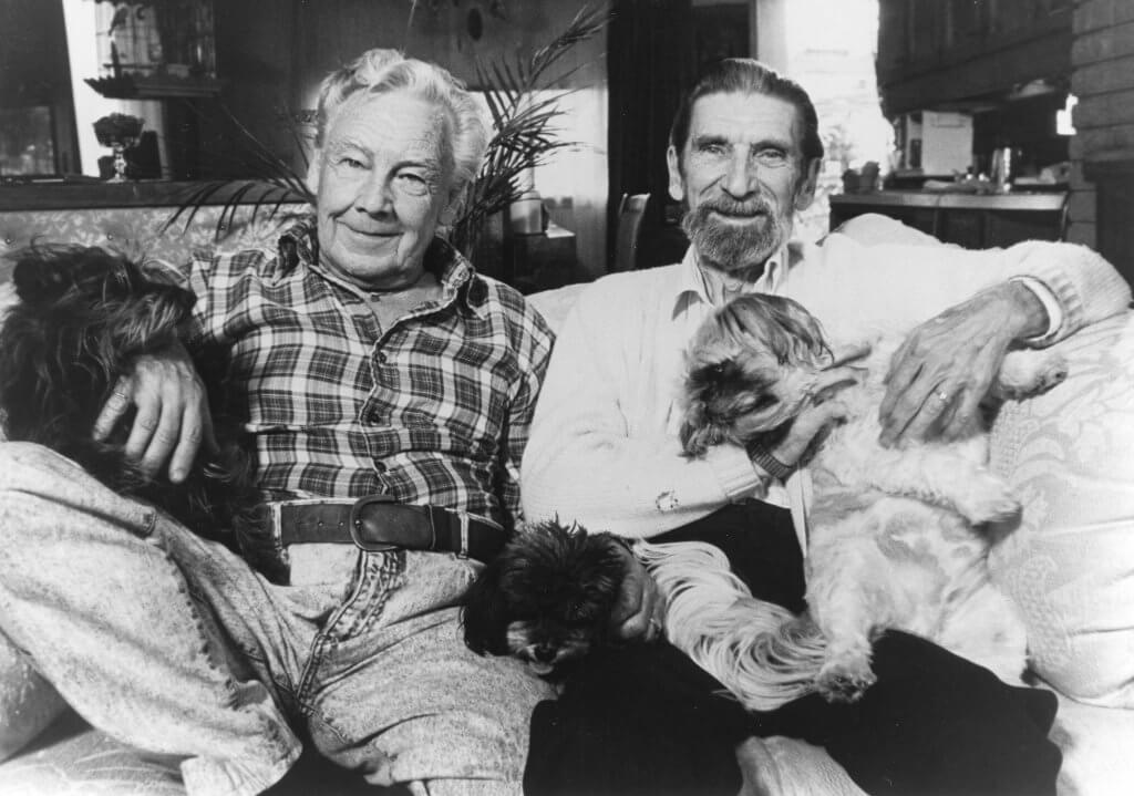 Jim Egan and his partner sit on a couch with their dogs.