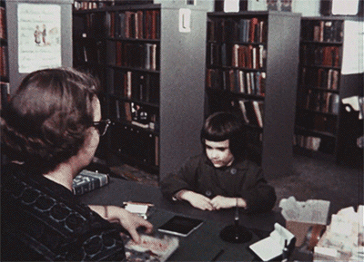 Woman giving a book to little girl.