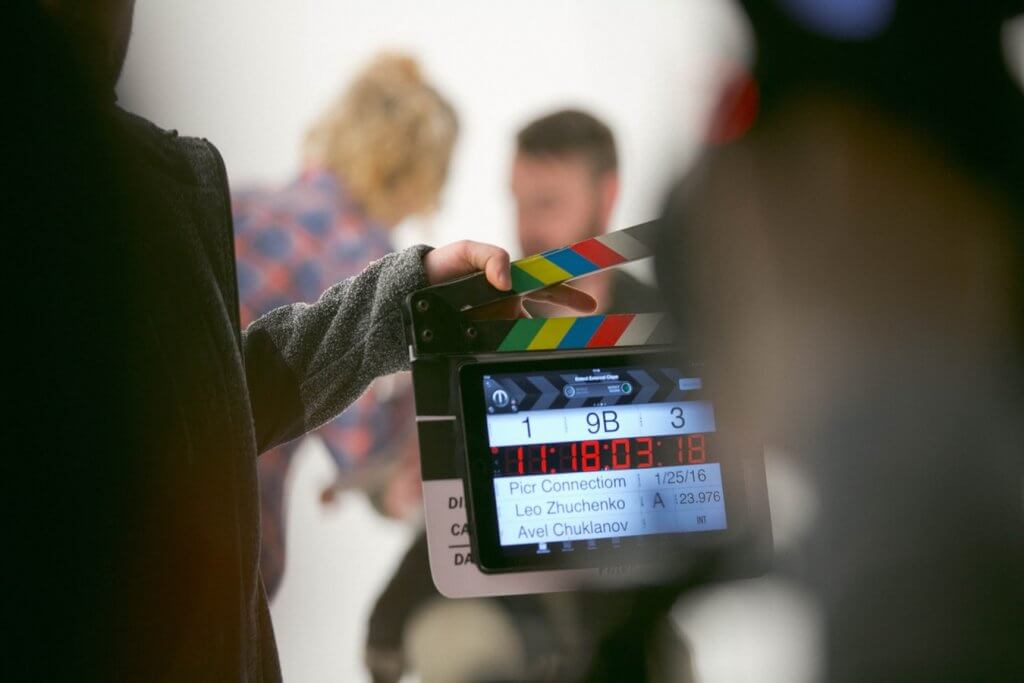 Film clapperboard and actors out of focus on movie set