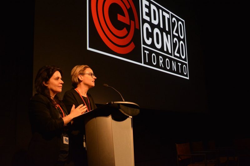 Two ladies speaking on a podium in front of projector screen that reads, "Editcon Toronto 2002"