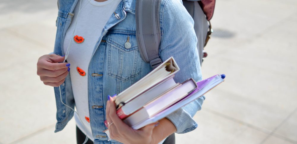 Girl holding a pile of books on her arm