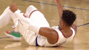 A New York Knicks player is helped onto his feet by his teammate after falling on the basketball court.