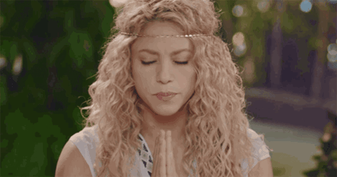 Shakira meditates with her hands in a prayer position, opens her eyes and looks side to side.