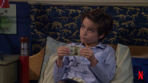 Max Fuller from "Fuller House" reclines in bed while pulling a paper bill.