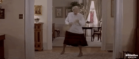 Robin Williams in "Mrs. Doubtfire" uses a broom as a mock guitar while dancing around a living room.