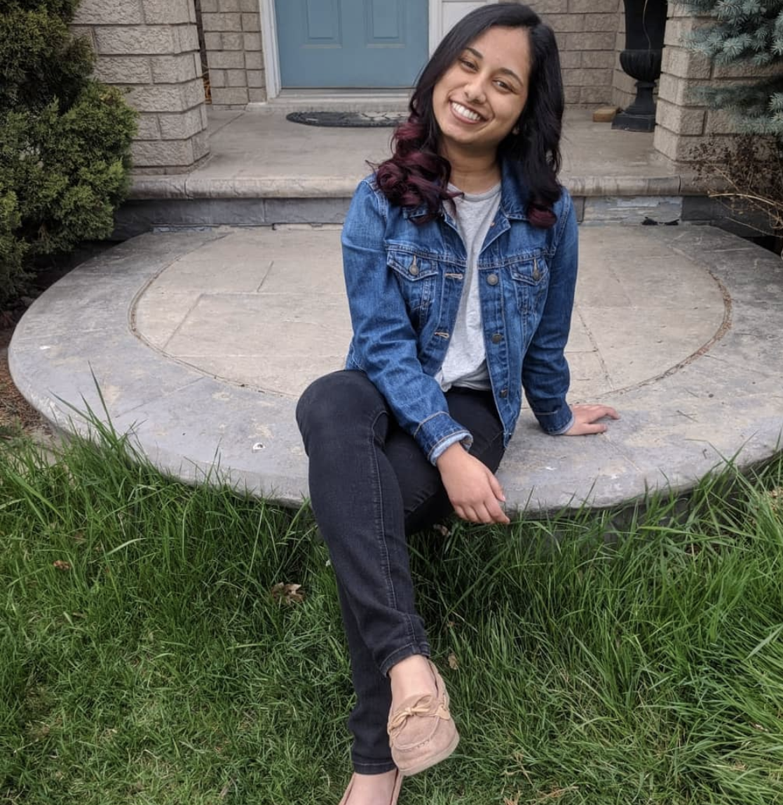 Third year Humber College Bachelor of Paralegal Studies student Judy Jaison sits outside and smiles while wearing a jean jacket.