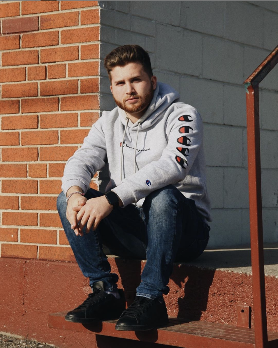 Third year University of Guelph-Humber Justice studies student Gianluca Tatone wears a grey hoodie while sitting in front of a brick wall.