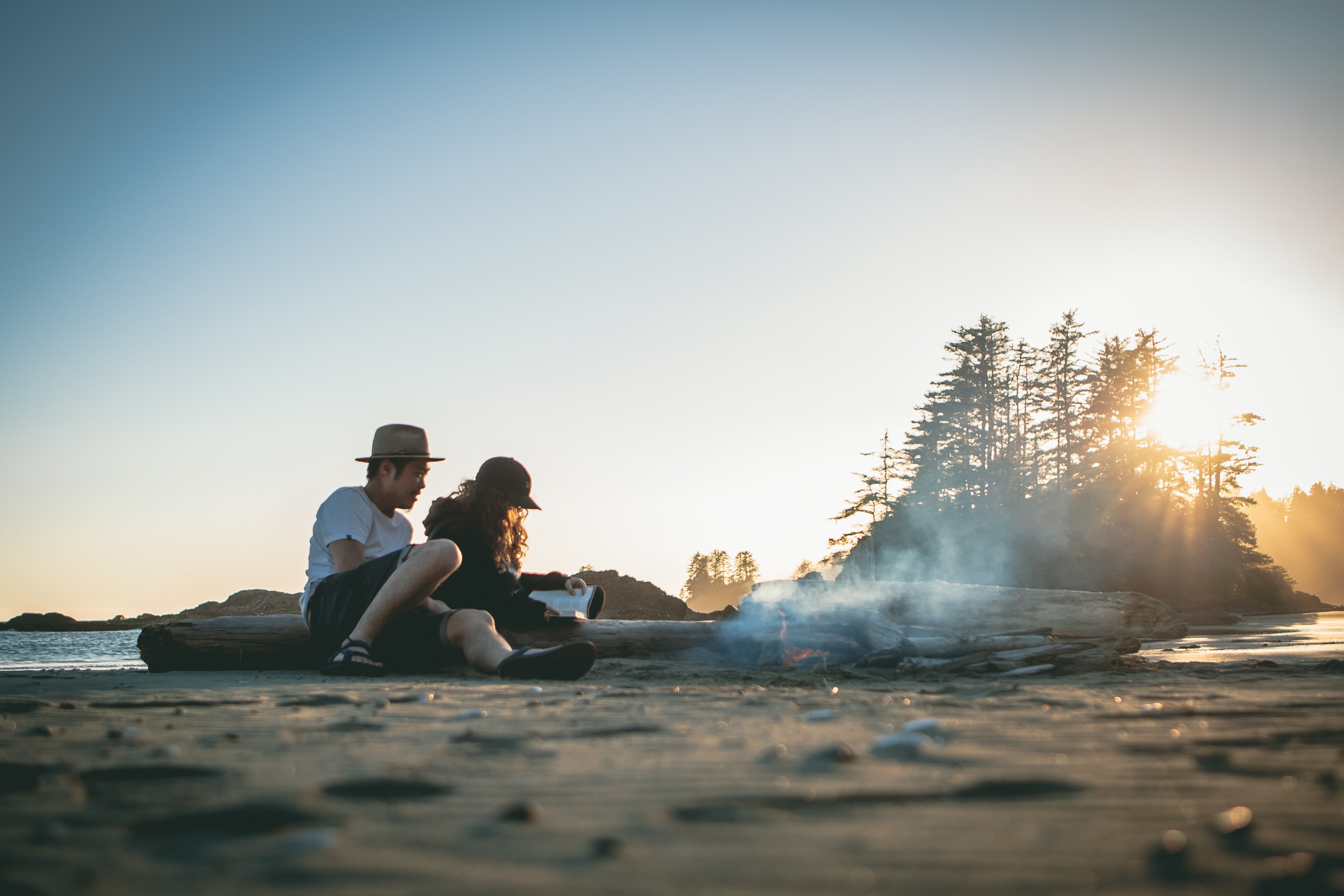 Man and woman sit on a log at the beach