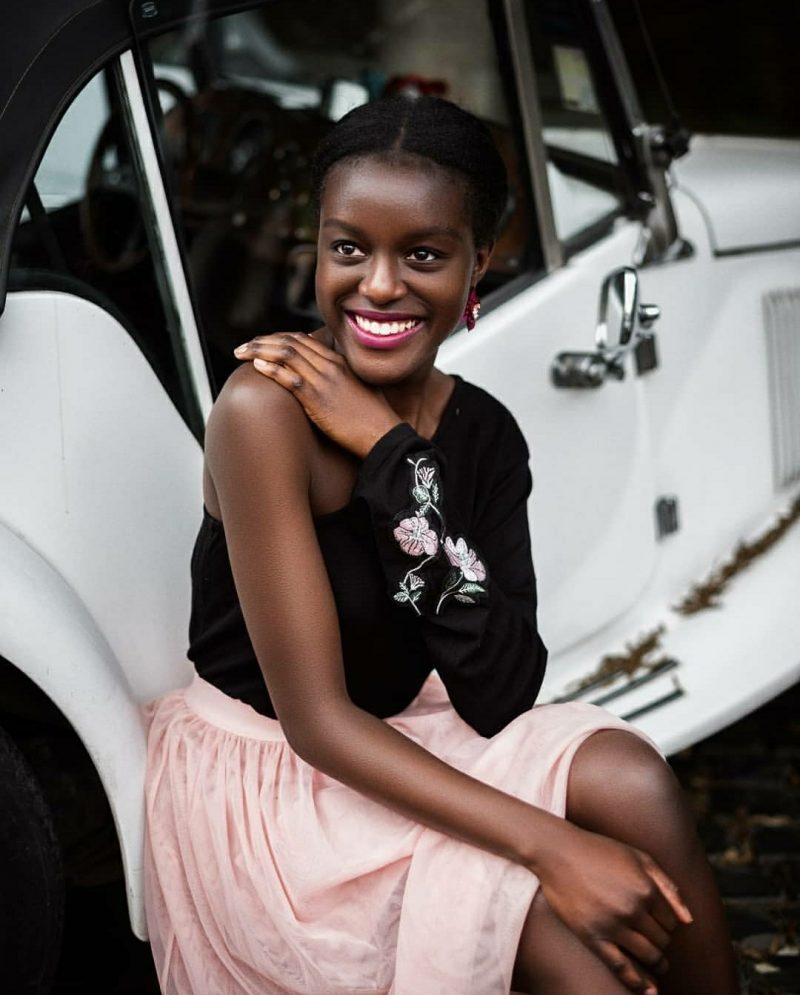 Photo of Universal Music intern, Maya Marcus, smiling and sitting on a white car.