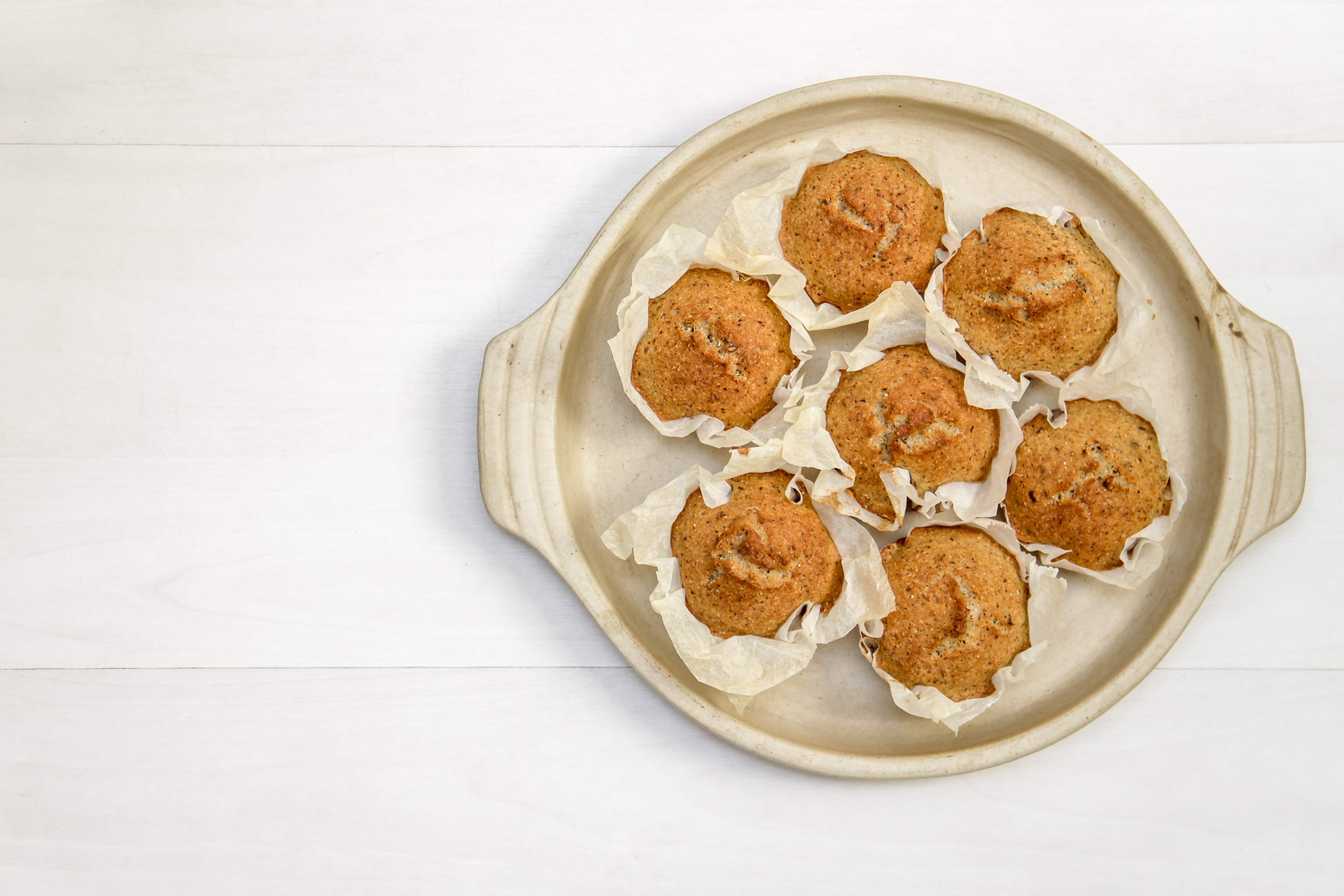 Seven muffins are arranged in a circular shape on a white tray.