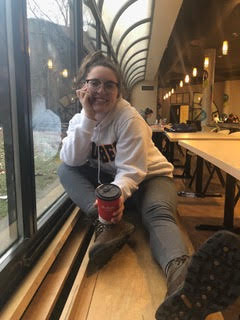 IGNITE 2020-2021 Board of Directors member Gabi Hentschke wears a white Humber College sweater and grey sweatpants while smiling and holding a Tim Hortons coffee cup.