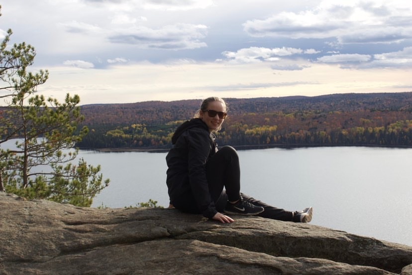 University of Guelph-Humber Justice Studies student Julia Widmer sits on a rock overlooking a lake.