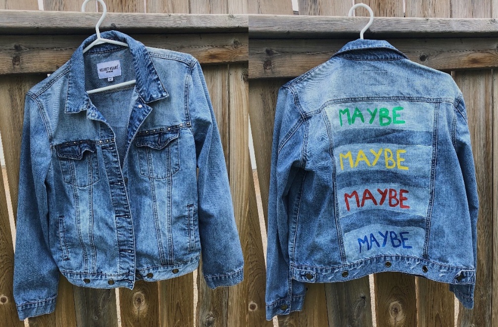 A denim jacket with the word "Maybe" painted in various colours on the back.