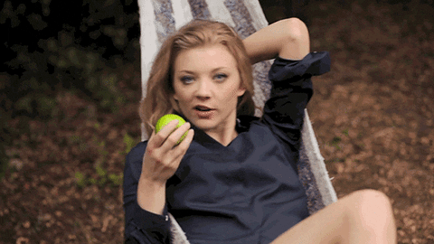 Natalie Dormer eats an apple in a hammock.
