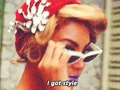 Singer Beyonce Knowles, with pinup-style hair and purple lipstick, lowers her white cat-eye sunglasses while saying, "I got style."