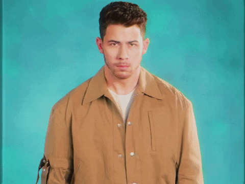 Nick Jonas puts his hands to his mouth with the words "Pretends to be shocked" appearing at the bottom of the screen.
