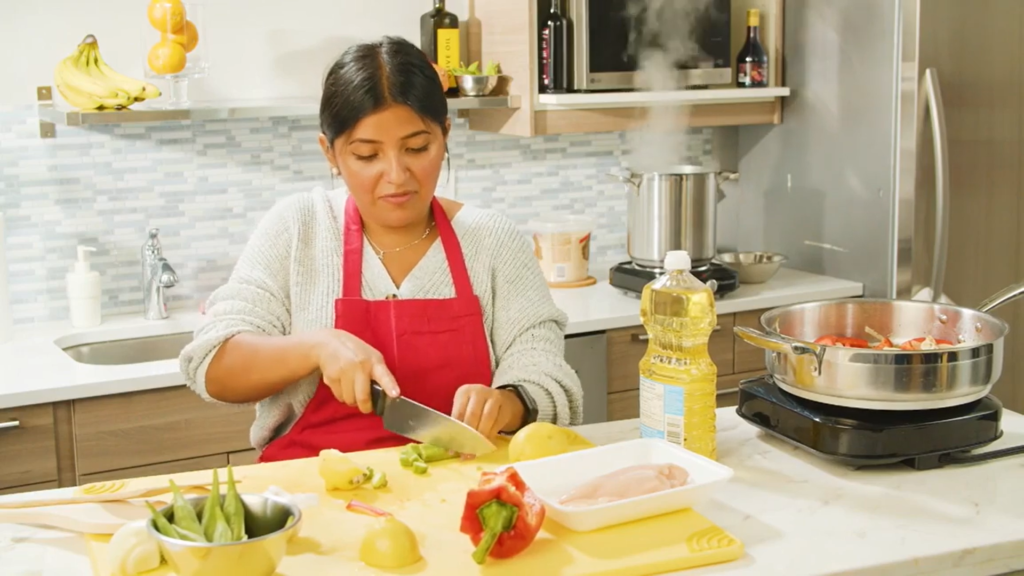 woman cutting okra on cutting board in a kitchen