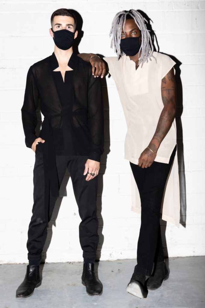 Two models against a white wall wearing black face masks
