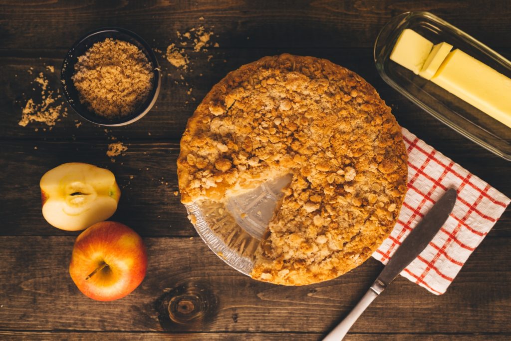 Apple pie, apples, cinnamon, and butter on a table