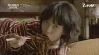 A girl eating black bean noodles.