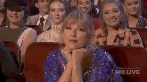 Taylor Swift leaning forward with head in hands and listening.