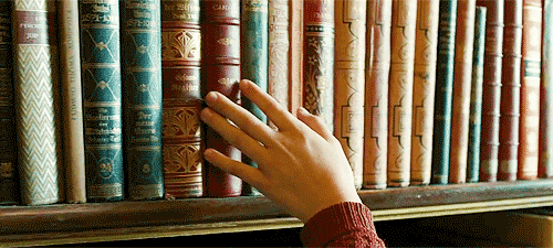 hand passing over bookshelf of books