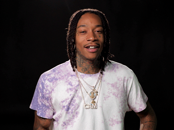 Wiz Khalifa holds his arms up and shrugs as if to say, "Oh well."