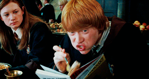 Ron Weasley from Harry Potter reading a book while eating. 