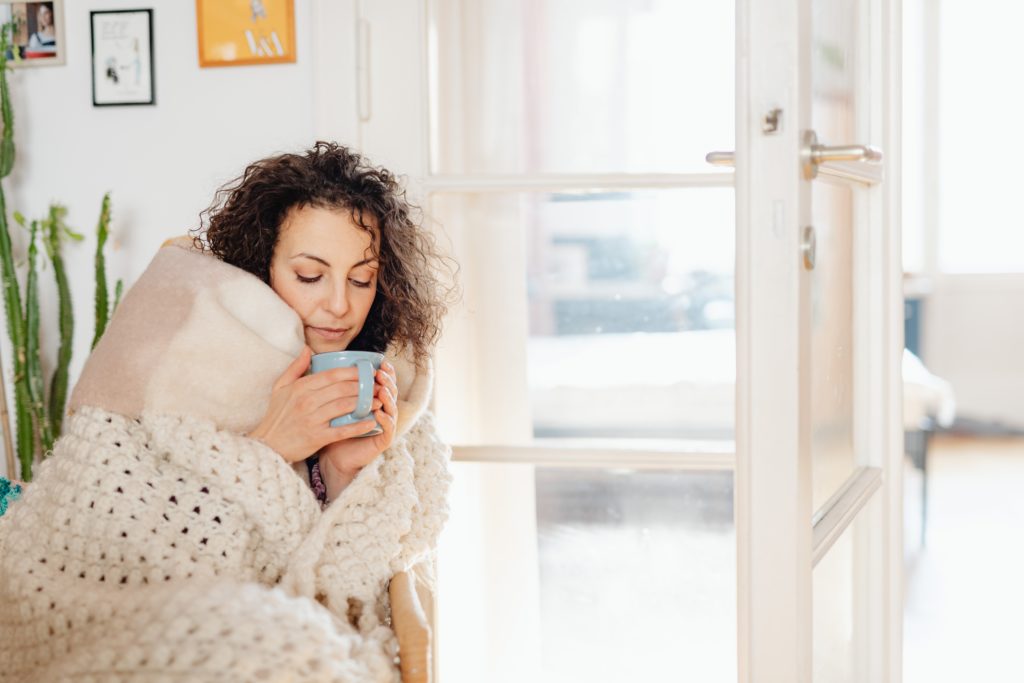Woman wrapped in blanket drinking out of mug