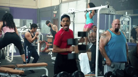 Chance the rapper dancing in gym with weights in his hands.